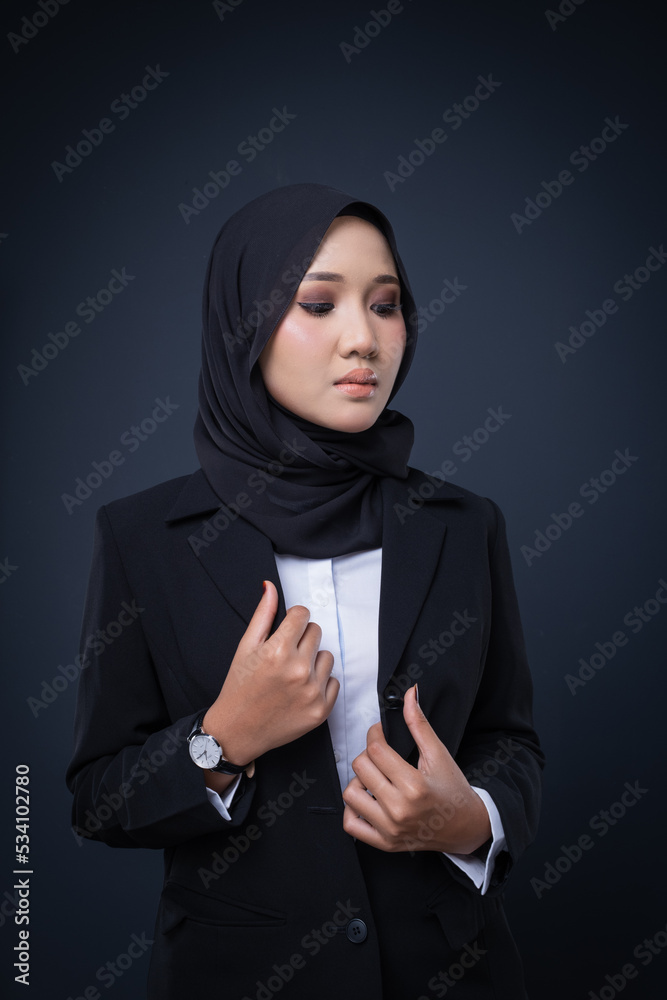 Portrait of an attractive Muslim woman wearing business attire and hijab with a corporate pose isolated on grey background. For image cut-out for technology, business or finance. Portrait of an attractive Muslim woman wearing business attire and hijab with a corporate pose isolated on grey background. For image cut-out for technology, business or finance.