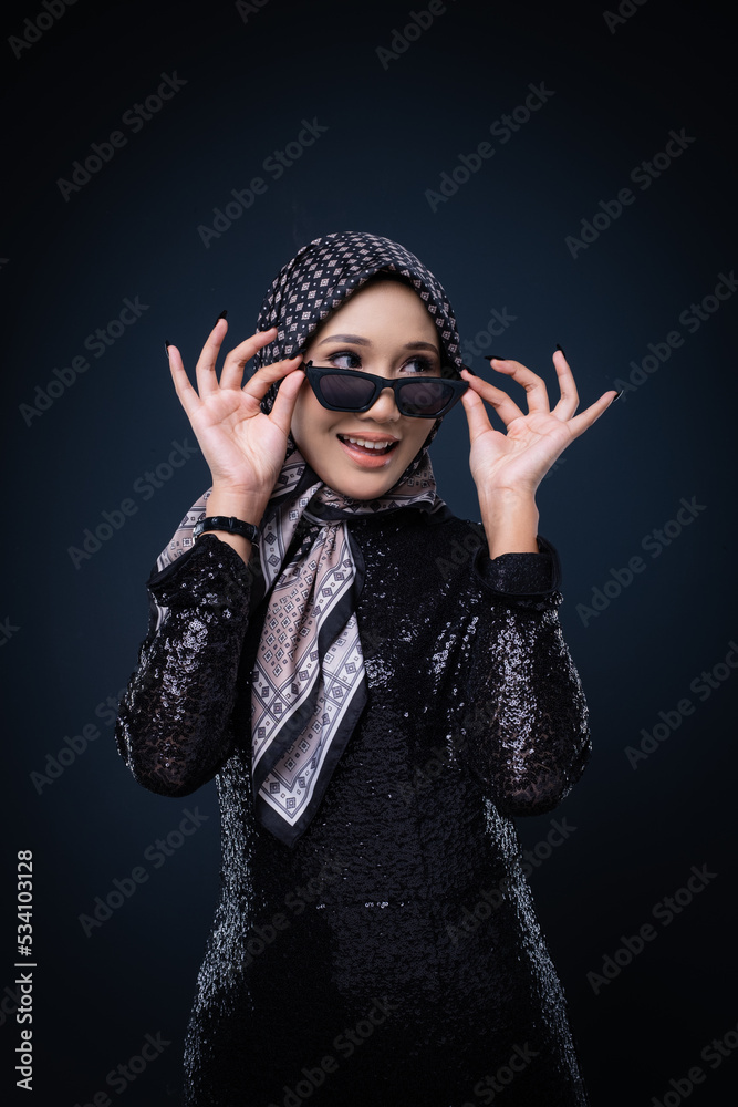 Portrait of a beautiful female model wearing hijab, a lifestyle apparel for Muslim women isolated on grey background. Idul Fitri and hijab fashion concept.