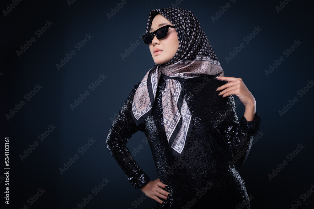 Portrait of a beautiful female model wearing hijab, a lifestyle apparel for Muslim women isolated on grey background. Idul Fitri and hijab fashion concept. Portrait of a beautiful female model wearing hijab, a lifestyle apparel for Muslim women isolated on grey background. Idul Fitri and hijab fashion concept.