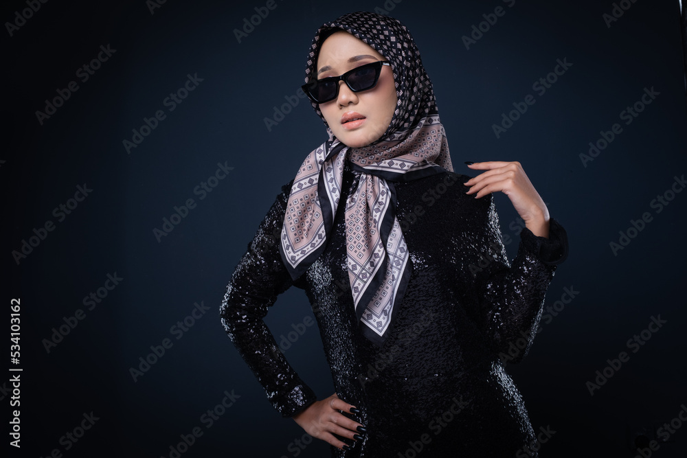 Portrait of a beautiful female model wearing hijab, a lifestyle apparel for Muslim women isolated on grey background. Idul Fitri and hijab fashion concept. Portrait of a beautiful female model wearing hijab, a lifestyle apparel for Muslim women isolated on grey background. Idul Fitri and hijab fashion concept.