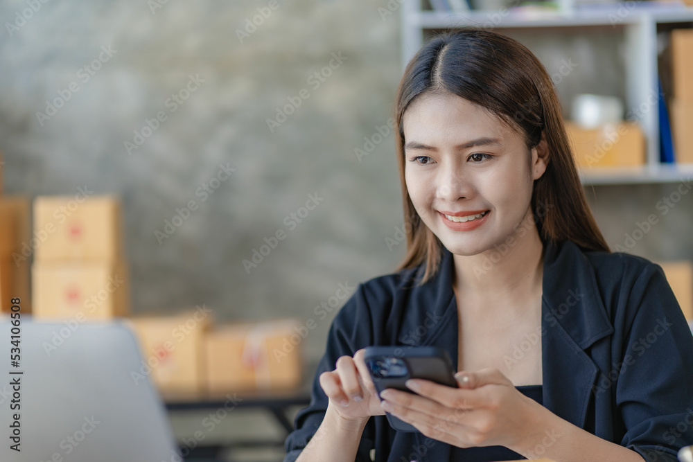 Fototapeta premium Beautiful Asian girl freelance SME business online shopping working on computer, laptop, smartphone with parcel box at home - online SME business idea and delivery.