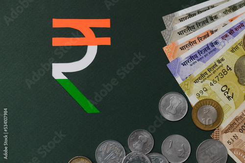 paper cut indian rupee symbol in tricolor with currency background. Flat lay, top view.  photo