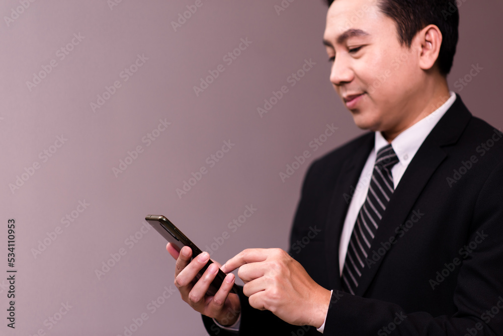Asian business men hand holding mobile phone on gray background Asian business men hand holding mobile phone on gray background