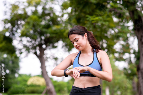 Sporty young woman using smart watch for running and checking device at outdoor