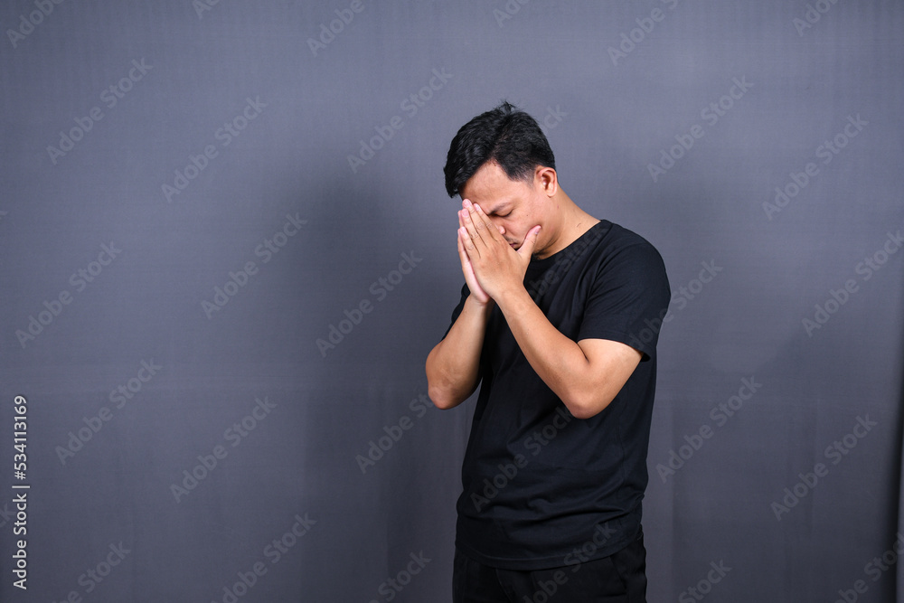sad man with hands on face in sadness, isolated on gray background, copyspace