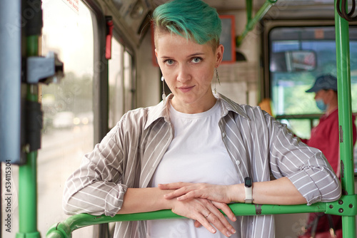 woman with green hair and white clothes rides a bus.