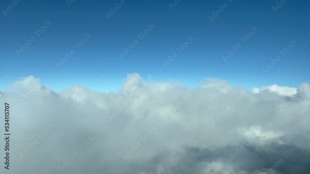 Aerial shoot from a jet cockpit while flying through layers of thin stratus with a deep blue sky. Pilot point of view. 4K.