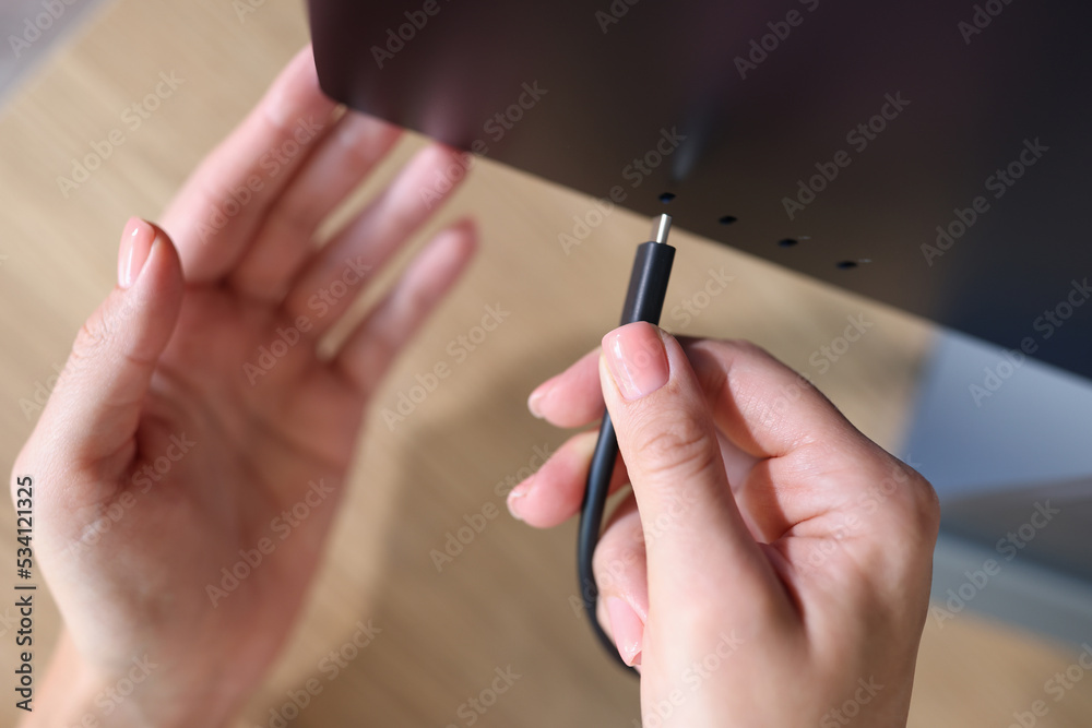 Person hand connects a black USB-C or Type C power cable to computer Person hand connects a black USB-C or Type C power cable to computer
