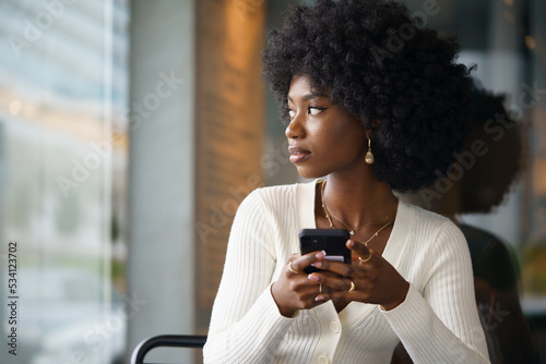Young afro woman using mobile phone at coffee shop