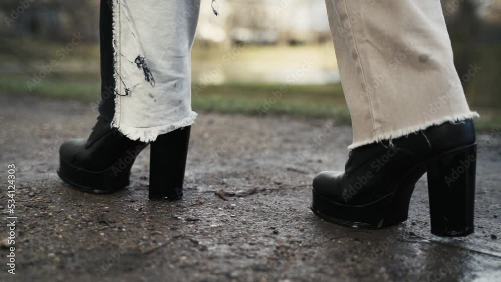 young woman in a black coat walking across a puddle in a park in autumn in afternoon young woman in a black coat walking across a puddle in a park in autumn in afternoon