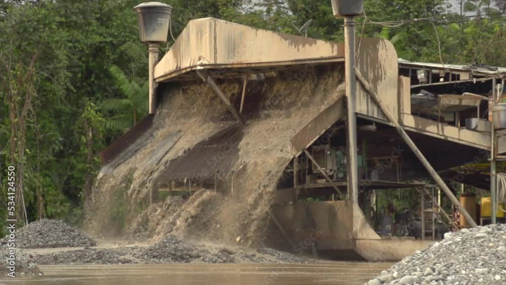Processed sand and mud spewing out of a gold dredger in to the river in Checo, Colombia. Slow motion. Wide shot. Processed sand and mud spewing out of a gold dredger in to the river in Checo, Colombia. Slow motion. Wide shot.