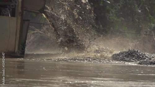 Processed sand spewing out of a gold dredger in to the river in Checo, Colombia. Slow motion. photo