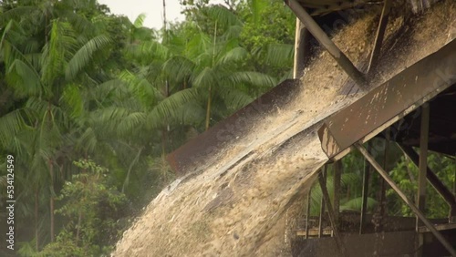 Processed sand and mud spewing out of a gold dredger in to the river in Checo, Colombia. Slow motion. photo