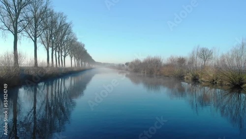 Drone shot dolly forward juste above de water on the Scheldt river next Escanaffles in the morning with smog and nice light photo