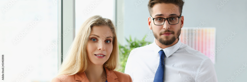Pair of modern businesspeople in office debate on financial issue, hold documents Pair of modern businesspeople in office debate on financial issue, hold documents