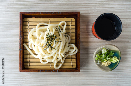 Chilled Zaru Udon, noodles with cut roasted seaweed served in a bamboo basket with a refreshing mentsuyu dipping sauce, wasabi, ginger and Bunching Onion. Top View photo