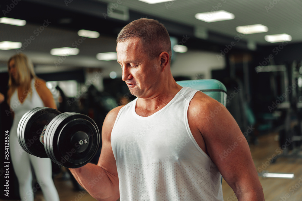 Middle-aged fit muscular man training in a sports gym