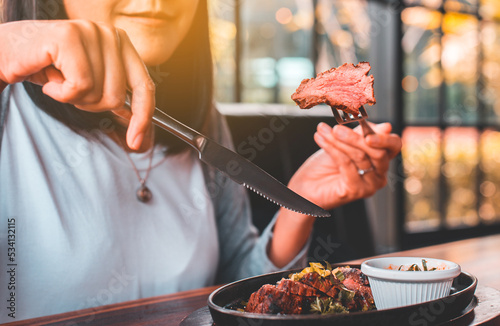 Happy woman enjoy eating with medium rare steak in restaurant