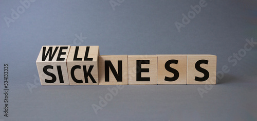 Wellness and Sickness symbol. Turned cubes with words sickness and wellness. Beautiful grey background. Business and wellness and sickness concept. Copy space © Natallia