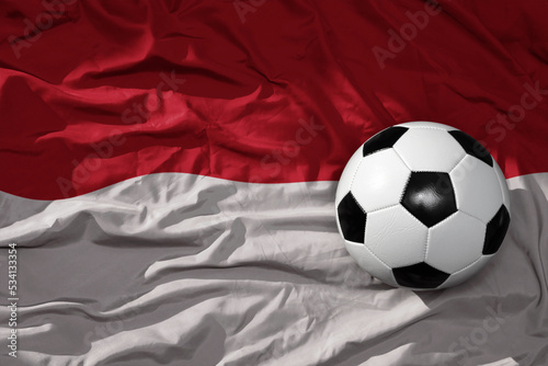 vintage football ball on the waveing national flag of indonesia background. 3D illustration