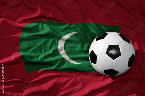 vintage football ball on the waveing national flag of maldives background. 3D illustration