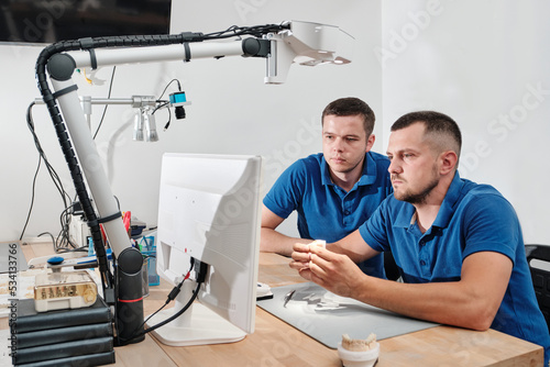 Dental technicians producing dental prosthesis under the microscope. The concept of prosthetics and implantology.