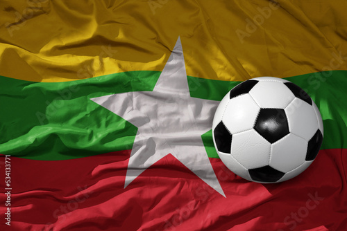vintage football ball on the waveing national flag of myanmar background. 3D illustration