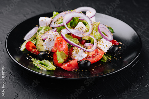Slika na platnu Greek salad in black bowl on stone