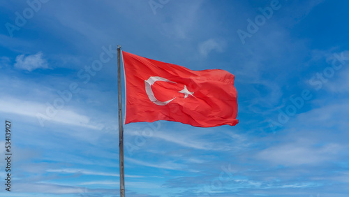 Turkish flag waving in a cloudy blue sky background.