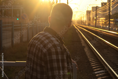 man waiting for the train on the platform at sunset