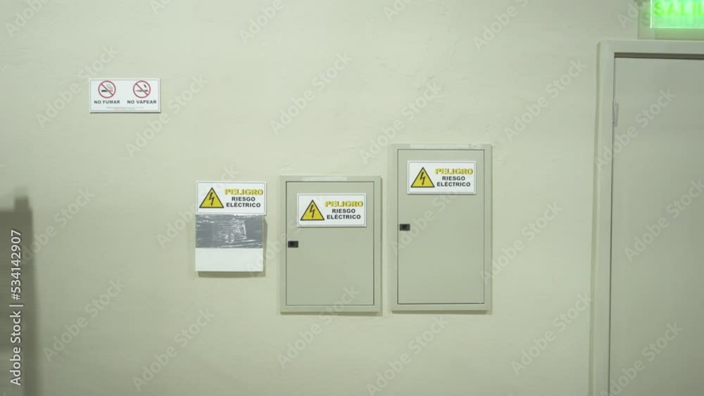 Wall with electrical panel and warning signs in a warehouse near the exit door Wall with electrical panel and warning signs in a warehouse near the exit door
