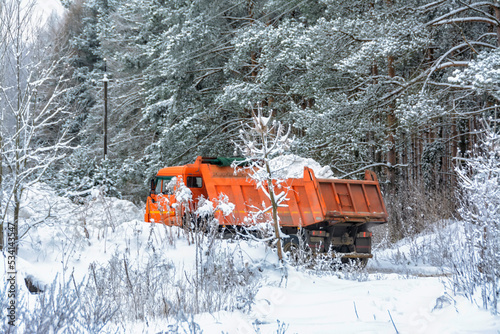 Snow removal from the city to the forest on an orange truck