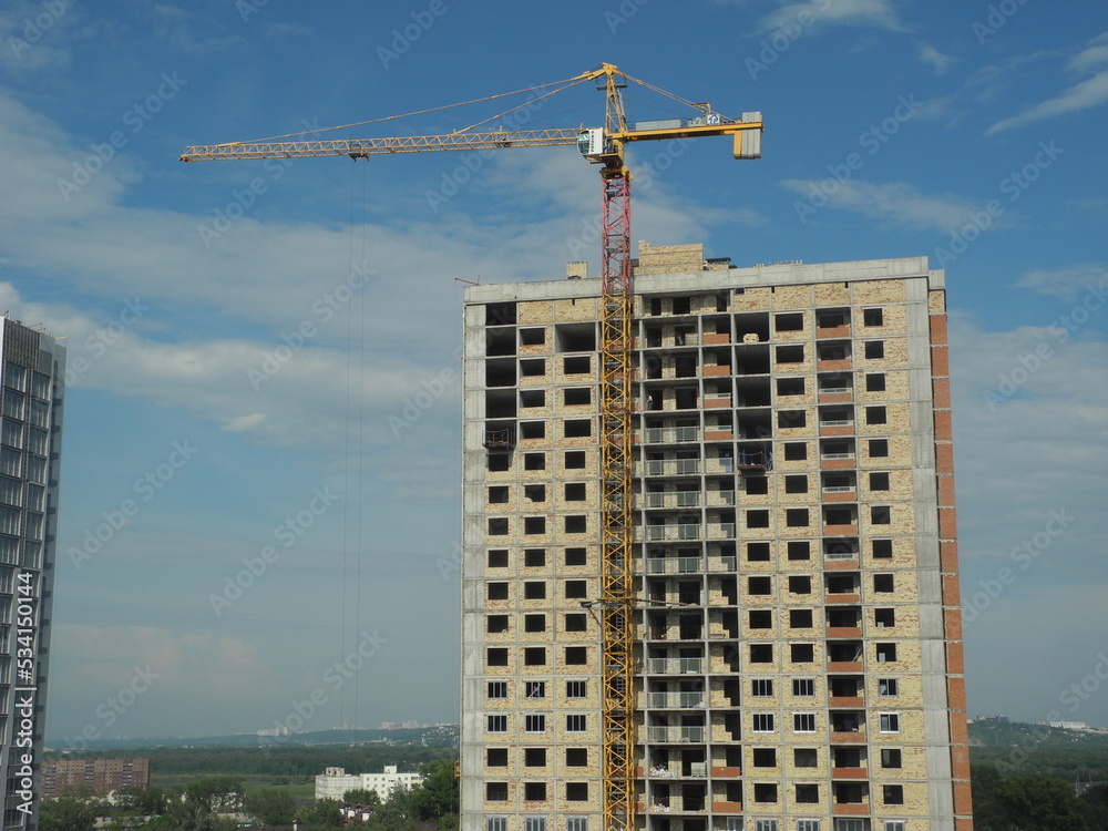 Crane and building under construction against blue sky Crane and building under construction against blue sky
