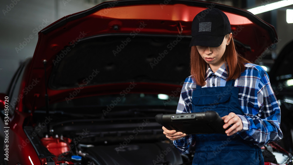 Caucasian female auto mechanic uses a special computer to diagnose faults. 