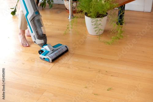 Fotografi woman with cordless wet vacuum cleaner cleans floor