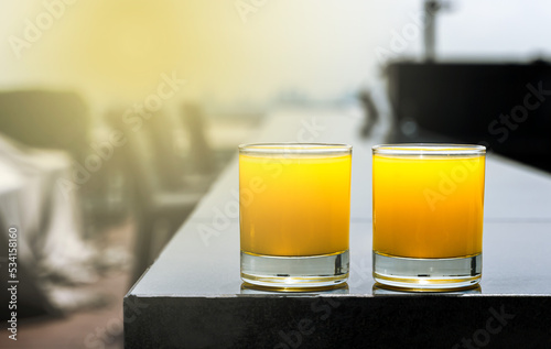 Close up glass of orange cocktails at rooftop bar and restaurant with sun flare, Bartender Concept