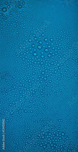 Water drops on blue background. Fresh clean texture, cold surface. Large and small drops of water on the glass