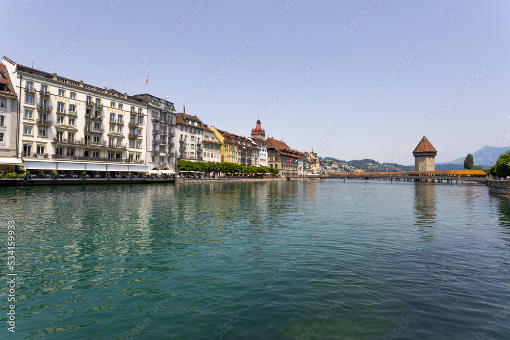 LUCERNE, SWITZERLAND, JUNE 21, 2022 - View of the old buildings and the wodden covered Kapellbrucke Bridge on the background on the Reuss river in city center of Lucerne, Switzerland