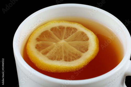 Bilde på lerret Tea with lemon in a white cup. Tea on a black background