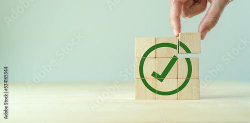 Corporate regulatory and compliance. Goals achievement and business success. Task completion. Ethical corporate. Do the right thing. Quality and ISO symbol. Wooden cube with green checkmark icon. photo