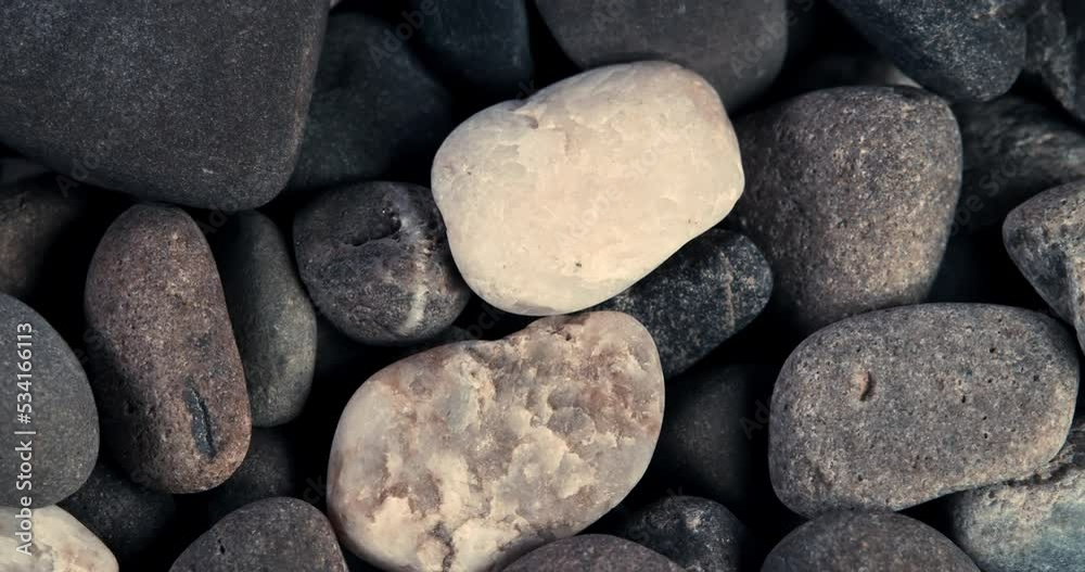 Sea stones background. Sea pebble. Smooth movement of stones background. Multi-colored sea stones shimmer in the sun. Sea stones background. Sea pebble. Smooth movement of stones background. Multi-colored sea stones shimmer in the sun.