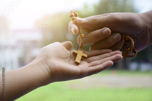 A rosary necklace with a cross placed on palm of a Christian, an idea for consecrating a sacred object of their own religion to invite other religious people to be in the christian religion.