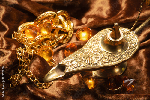Magic lamp and jewels on the old wooden table background.