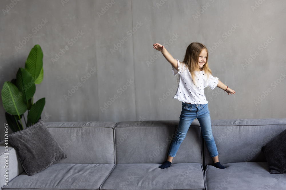 Adorable small little girl jumping at home on sofa