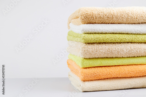 A stack of clean towels on a light gray background. Cotton towels on table. Space for text