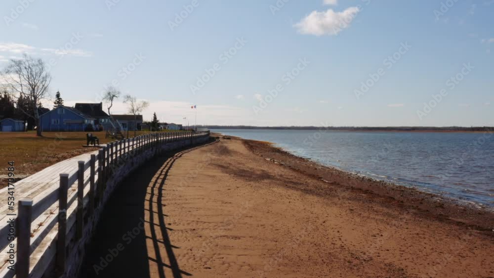 Aerial drone shot slowly traveling toward acadian flag on waterfront shore, small village, eastern Canada. Aerial drone shot slowly traveling toward acadian flag on waterfront shore, small village, eastern Canada.