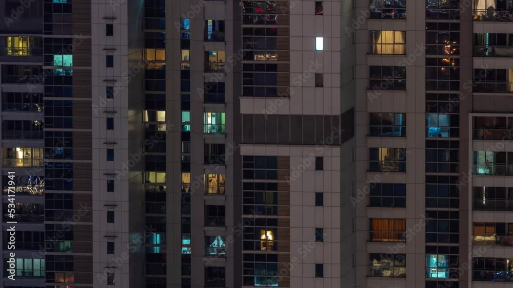 Apartment windows of a glazed skyscraper glow at night with city lights reflection aerial timelapse. Illuminated towers in business district Apartment windows of a glazed skyscraper glow at night with city lights reflection aerial timelapse. Illuminated towers in business district