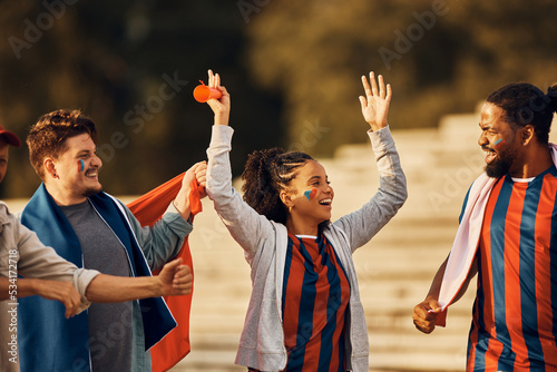 Happy black sports fan and her friends celebrate on street during soccer world cup.