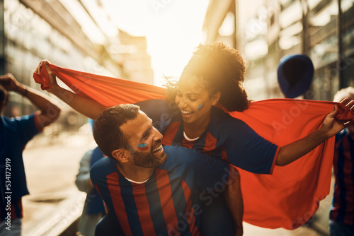 Happy sports fan piggybacking his African American girlfriend during soccer world championship. photo