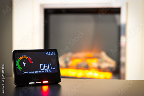 Smart meter showing high energy costs and an electric fire in the background photo